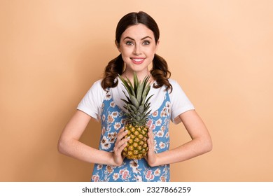Photo of young girl funny curls ponytails wear dress presenting her favorite fruit pineapple sweet flavor isolated on beige background