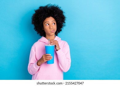 Photo of young girl look empty space curious unsure think drink cola isolated over blue color background - Powered by Shutterstock