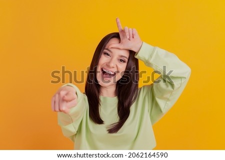 Photo of young girl mocking point finger bully fooling childish isolated over yellow color background