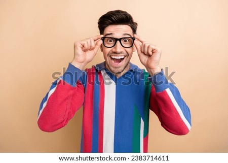 Photo of young guy wearing new optician goggles spectacles surprised reaction how his vision corrected isolated on beige color background