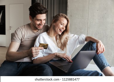 Photo of young happy loving couple in home indoors on sofa using laptop computer holding credit card. - Powered by Shutterstock