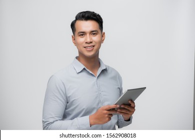 Photo of young happy man standing over white background using tablet computer.