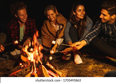 Photo of a young happy positive group of friends at night holding marshmallow in fire outdoors. - Powered by Shutterstock