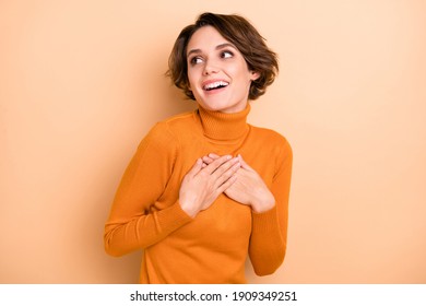 Photo of young happy positive lovely dreamy girl hear compliment hold hands chest isolated on beige color background