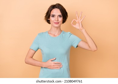 Photo of young lady arm on belly show fingers okey symbol good promo isolated over beige color background