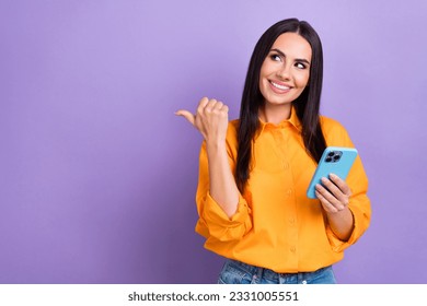 Photo of young lady blogger hold apple iphone direct finger looking empty space point finger itunes update isolated on purple background