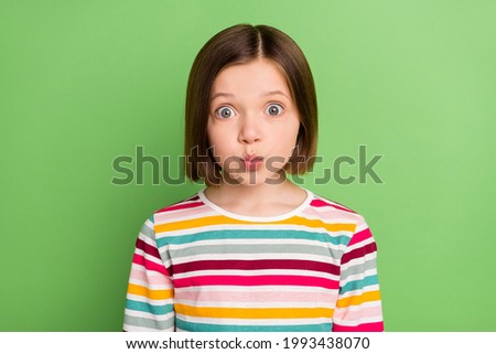 Photo of young little girl happy positive smile pouted lips amazed surprised isolated over green color background