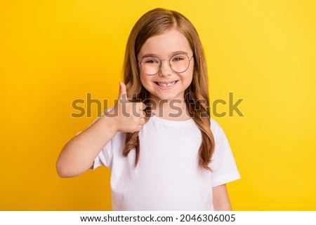 Photo of young little girl happy positive smile show thumb-up like fine recommend ad isolated over yellow color background