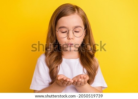 Photo of young little girl pouted lips send air kiss you romance feelings isolated over yellow color background