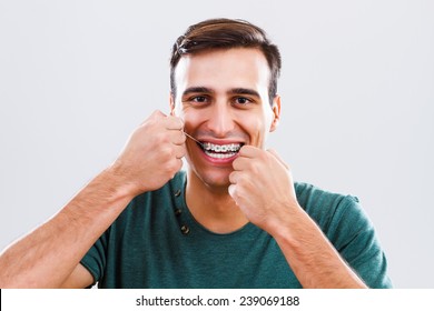 Photo Of Young Man With Braces Using Dental Floss.Dental Hygiene