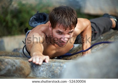 Photo of young man climbing up the rock