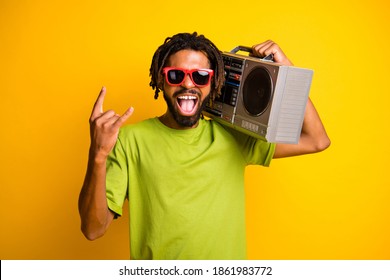 Photo of young man excited enjoy rock music show sign horn rocker hold boombox isolated over yellow color background
