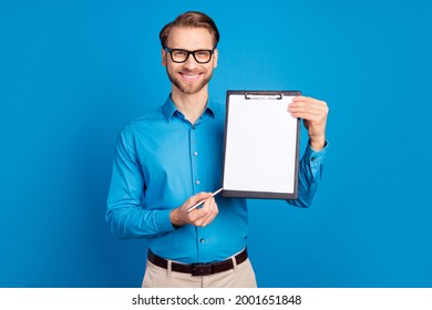 Photo of young man happy positive smile point pen clipboard document contract sign isolated over blue color background