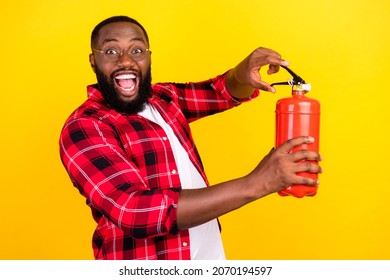 Photo of young man hold hands fire extinguisher wear glasses flame isolated on yellow color background