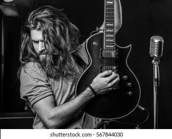 Photo of a young man with long hair and beard playing electric guitar on stage. - Powered by Shutterstock