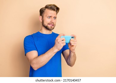 Photo Of Young Man Moody Anxious Play Game Mobile Bite Lips Failure Isolated Over Beige Color Background