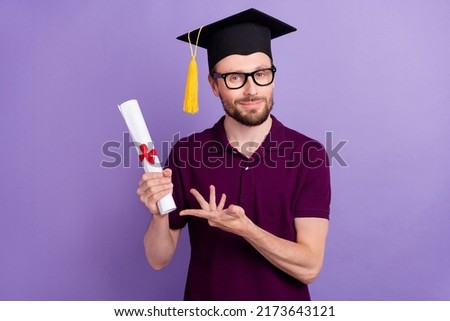 Photo of young man present show master diploma wear mortarboard isolated over violet color background