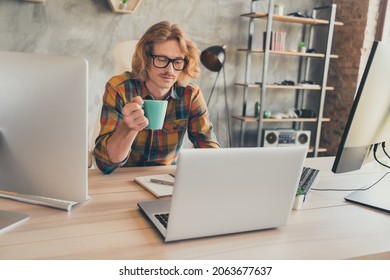 Photo Of Young Man It Specialist Read Browse Computer Sit Desk Office Drink Mug Cup Tea Coffee Relax Break Indoors