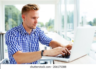 Photo of a young man typing on a laptop