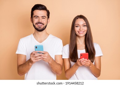 Photo of young married couple happy positive smile use cellphone chat type sms isolated over beige color background