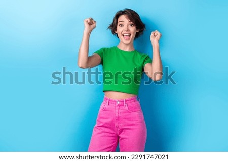 Photo of young overjoyed funny girl raise fists up scream yell successful victory competition first place isolated on aquamarine color background