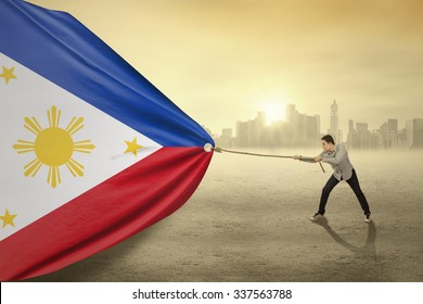 Photo of young person with casual clothes pulling Philippines national flag