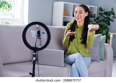 Photo of young positive influencer woman hold hand box blogger vlog sit sofa indoors inside house home - Powered by Shutterstock