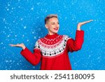 Photo of young positive woman wear red reindeer ornament hold palm choose product with more pros isolated on blue color background