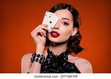 Photo of young pretty glamour charming woman cover eye cards ace play gamer isolated on dark orange color background