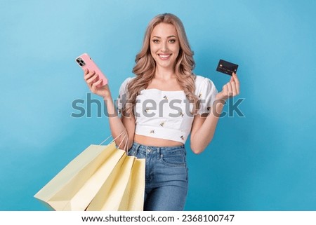 Photo of young shopaholic lady blonde holding plastic cashless ecard wireless nfc transaction purchase isolated on blue color background