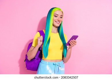 Photo of young smiling female college student studying using smartphone isolated on pink color background
