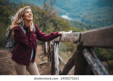 Photo of a young smiling woman carrying a backpack and hiking in the nature. Young woman breathing pure air in a forest. Happy hiker caucasian woman smile and enjoy the nature walking  - Powered by Shutterstock