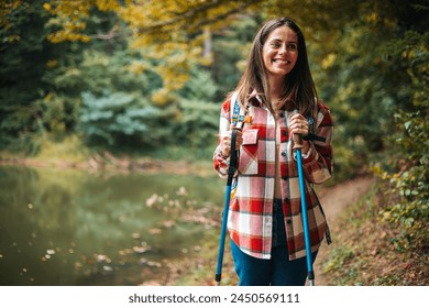 Photo of a young smiling woman carrying a backpack and hiking in the nature. Young woman breathing pure air in a forest. Happy hiker caucasian woman smile and enjoy the nature walking  - Powered by Shutterstock