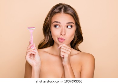 Photo of young thoughtful minded woman hold finger chin look at razor epilation depilation isolated on beige color background