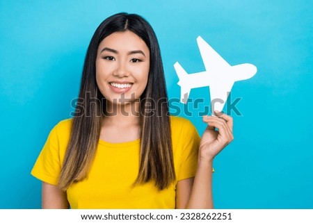 Photo of young vietnamese girl wear yellow t-shirt hold paper origami airplane flying abroad lowcost ad isolated on blue color background