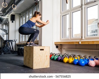 Photo of a young woman doing a box jump at the gym.