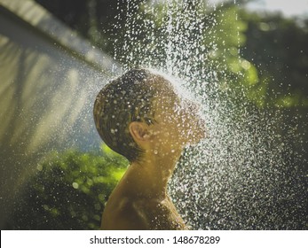 Photo of  young woman enjoying shower outdoors