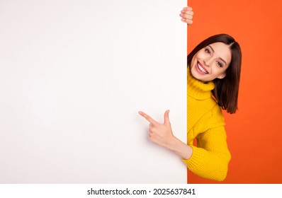 Photo of young woman happy positive smile point finger empty space billboard ad advice choice isolated over orange color background - Shutterstock ID 2025637841