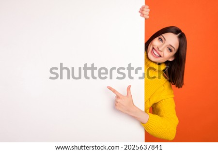 Photo of young woman happy positive smile point finger empty space billboard ad advice choice isolated over orange color background