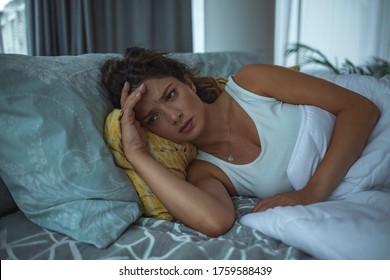 Photo Of A Young Woman Lying In Bed At Night, Wide Awake With A Case Of Insomnia. Depressed Woman Awake In The Night, She Is Touching Her Forehead And Suffering From Insomnia