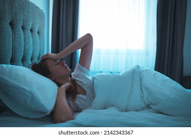 Photo of a young woman lying in bed at night, wide awake with a case of insomnia. Sleep disorder, insomnia. Young blonde woman lying on the bed awake 