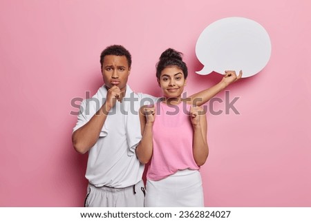 Photo of young woman and man go in for sport regularly stand next to each other dressed in activewear demonstrate blank speech bubble for your promotional text isolated over pink background.