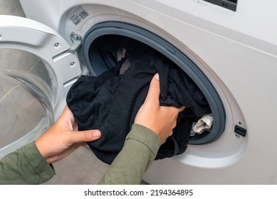 Photo Of A Young Woman Putting Laundry In A Washing Machine From Above