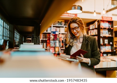 Photo of young woman reading impressum for book that she just grabbed from book shelf. Young woman is spending her free time at bookstore.