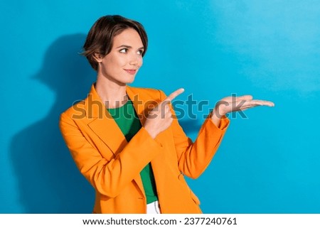 Photo of young woman realtor wear orange jacket hold arm pointing finger mockup cheap rent apartments isolated on blue color background