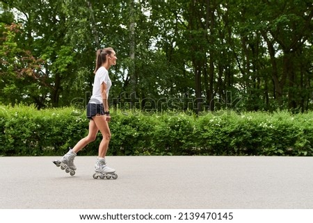 Photo of a young woman rollerblading in a park                               