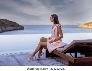 Photo Of A Young Woman Sitting Near Pool And Enjoying The View. Luxury Resort 