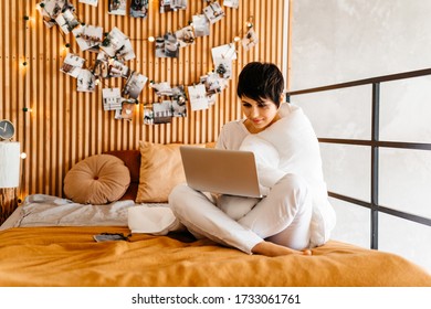 Photo Of A Young Woman Sitting On The Bed With Blanket Covered, Using Laptop Checking Email