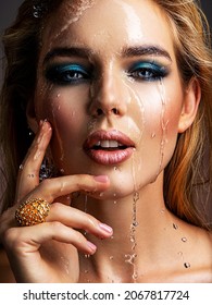 Photo of young woman with style make-up and water splashes  . Portrait of blonde woman with drops of water around her face. Sexy girl with blue eye makeup. Fashion model and water. Fashion concept. 