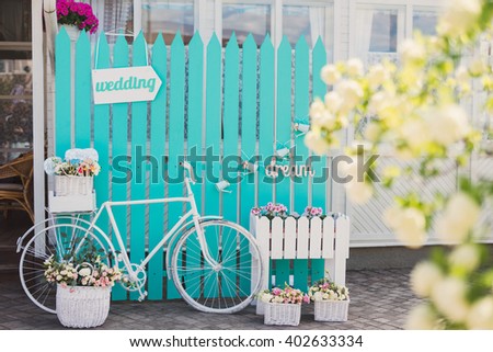 Photo zone for guests at wedding reception. White vintage bicycle, turquoise background, wooden 'wedding' pointer, flowers in baskets, 'dream' sign.